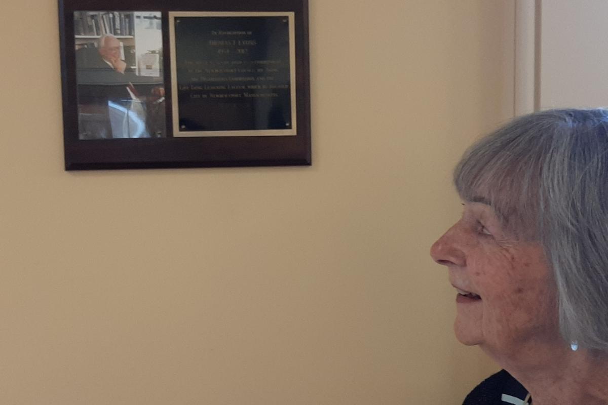 Woman looks at photo on wall plaque
