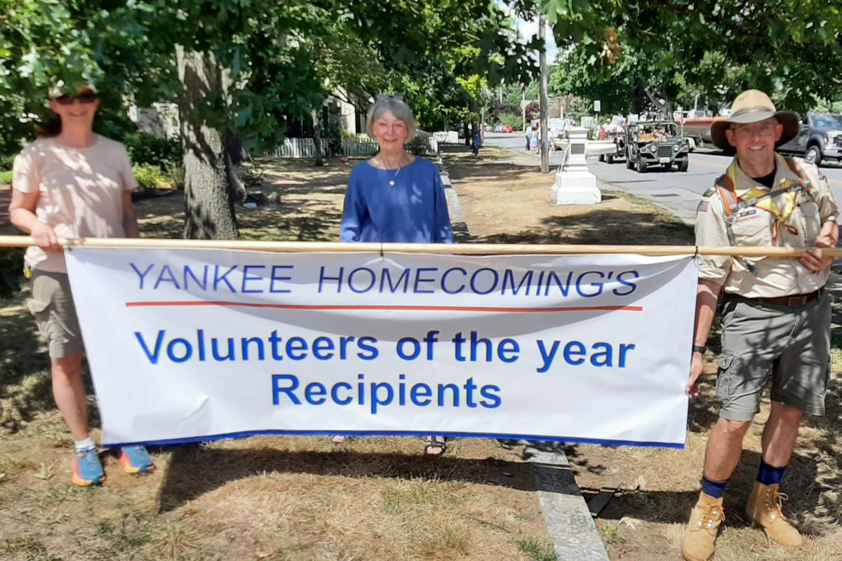 Woman stands behind Volunteers of the Year banner