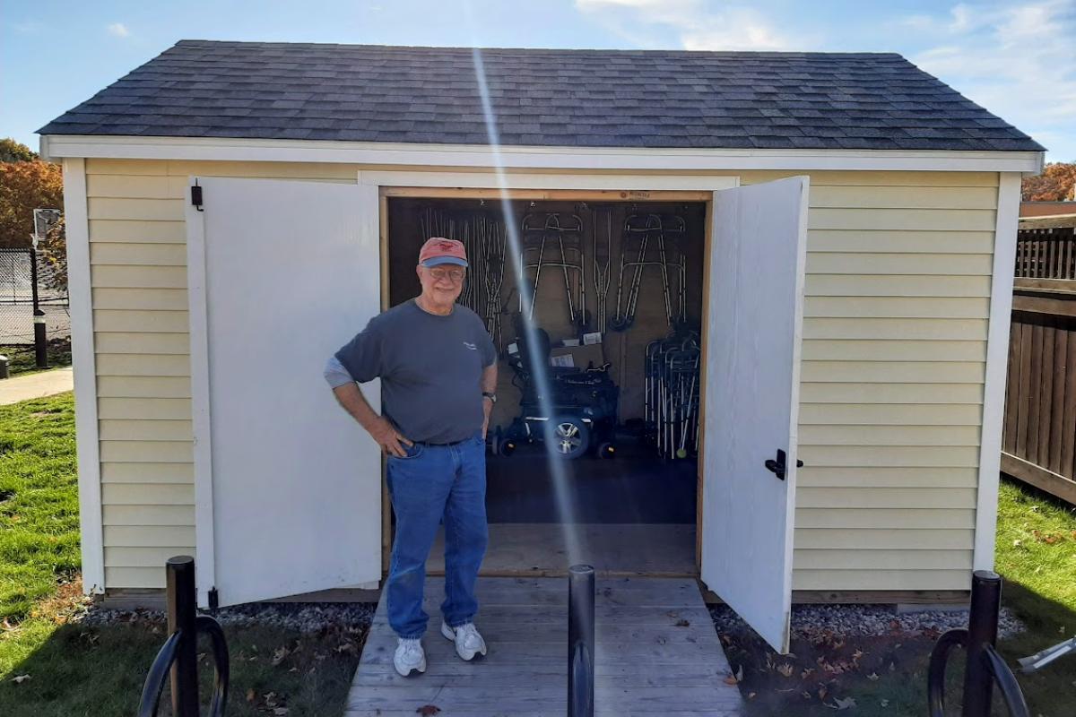 A man stands in front of an organized shed