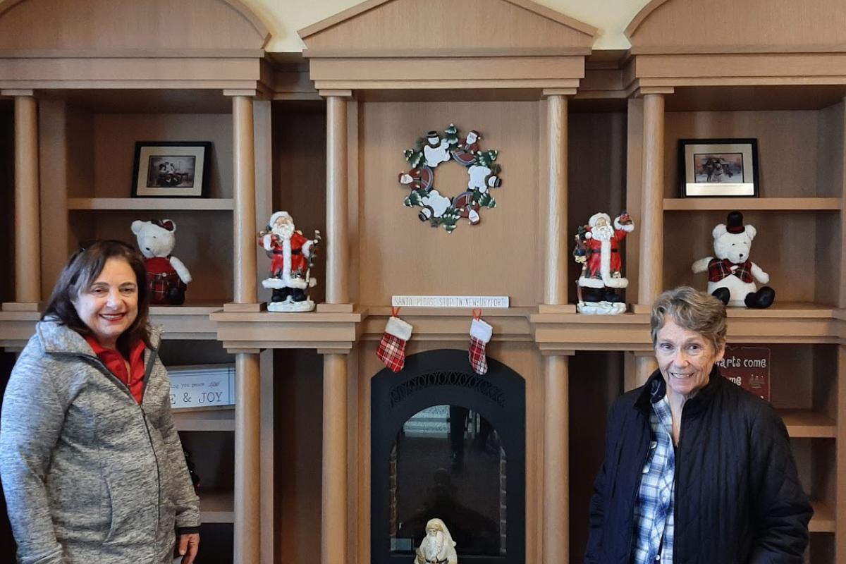 Two women stand in front of decorated shelves