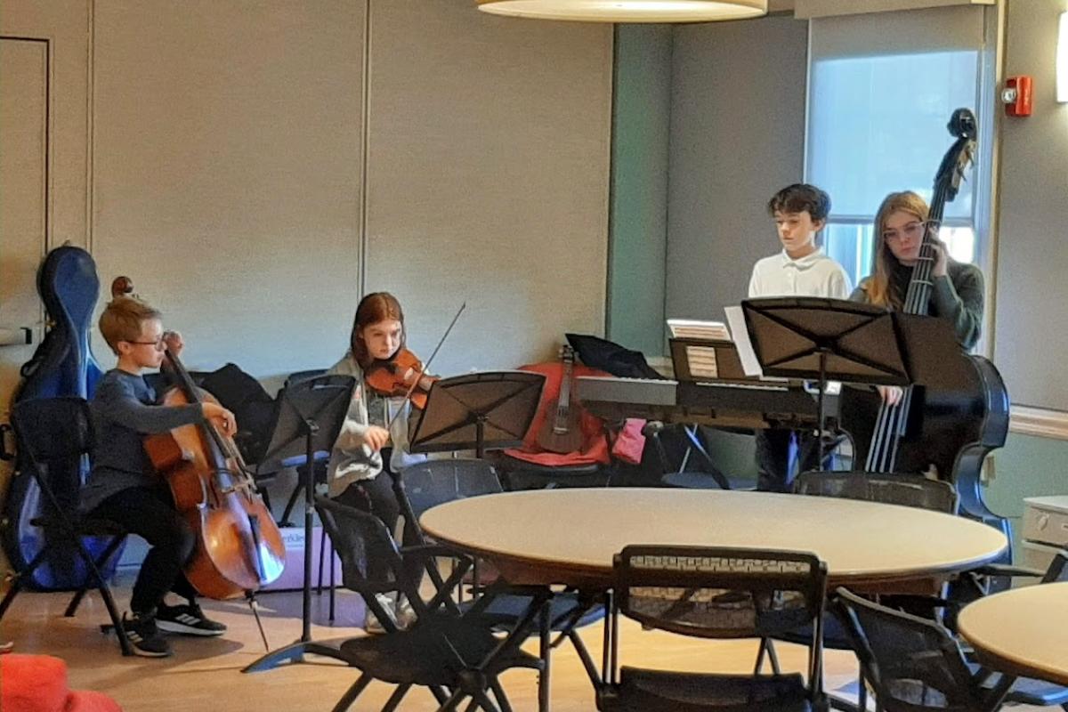 Four students perform as part of a middle school orchestra