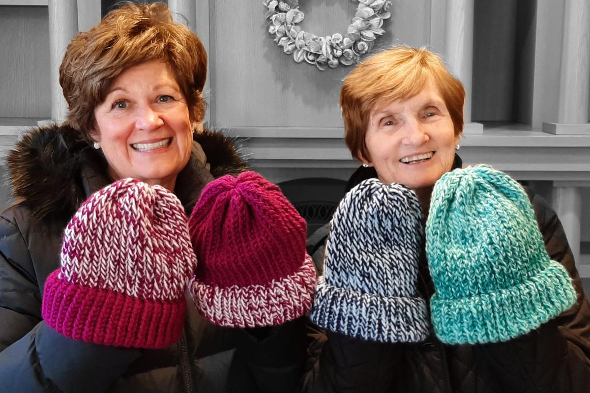 Two women show off colorful knit hats