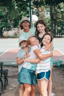 a group of girls are hugging with a staff person cheering behind