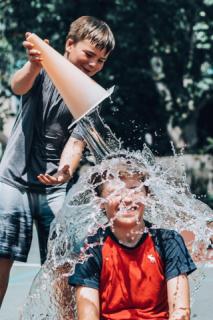 a child pouring water on another child's head