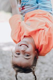 girl with pig tails smiling hanging upside down on playground