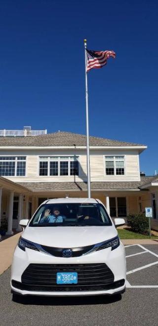 White Minivan with Building and Flag Behind