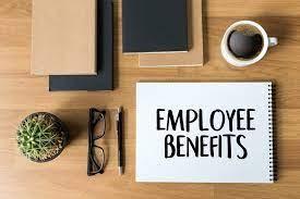 employee benefits text on desk with coffee, glasses, pen, tablet, books and a cactus plant.