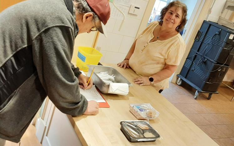 Woman presents meal to man at counter